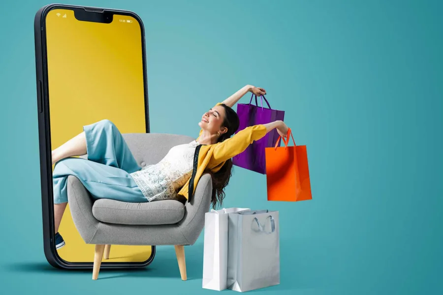 A happy woman holding shopping bags next to a giant iphone screen