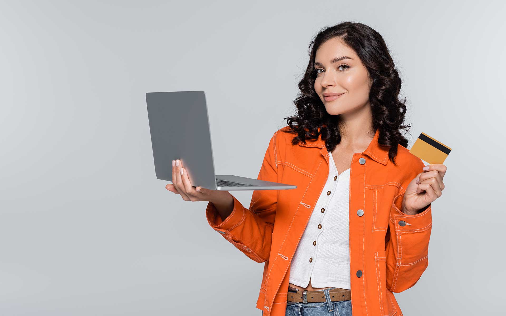A smiling woman holding an open laptop and a credit card